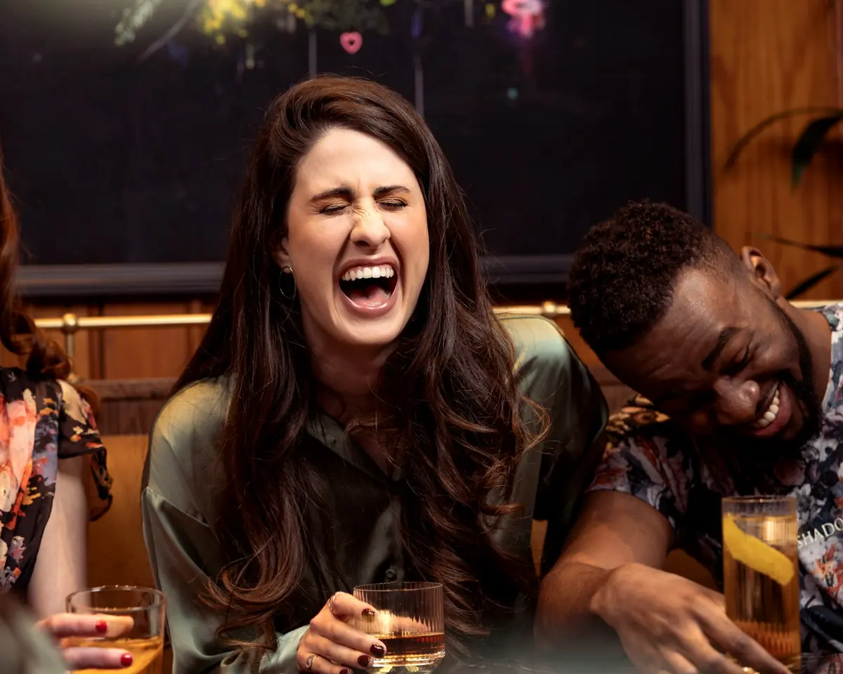 Friends bursting out laughing over drinks